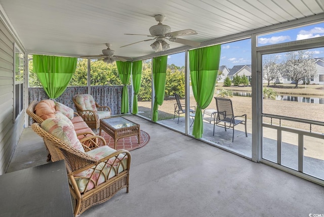 sunroom / solarium featuring a healthy amount of sunlight, a ceiling fan, and a water view