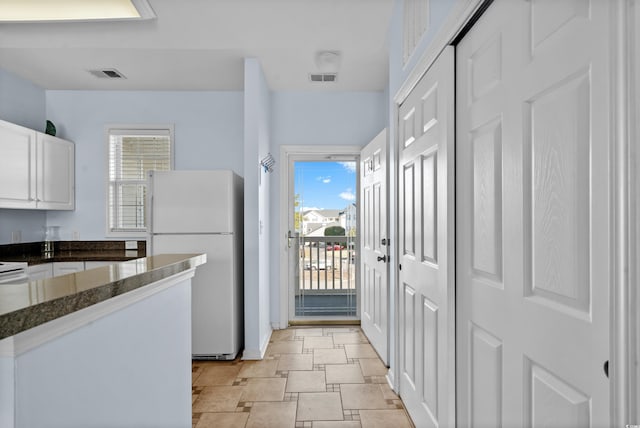 kitchen with visible vents, a healthy amount of sunlight, white cabinets, and freestanding refrigerator