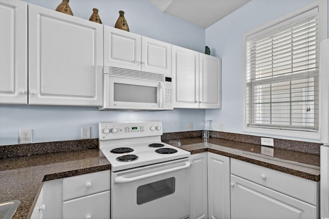 kitchen featuring white appliances, dark countertops, and white cabinets