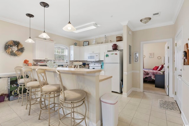4142 Hibiscus Dr Unit 104, Little River, SC 29566 - kitchen featuring white appliances, light tile patterned floors, a breakfast bar, a peninsula, and ornamental molding