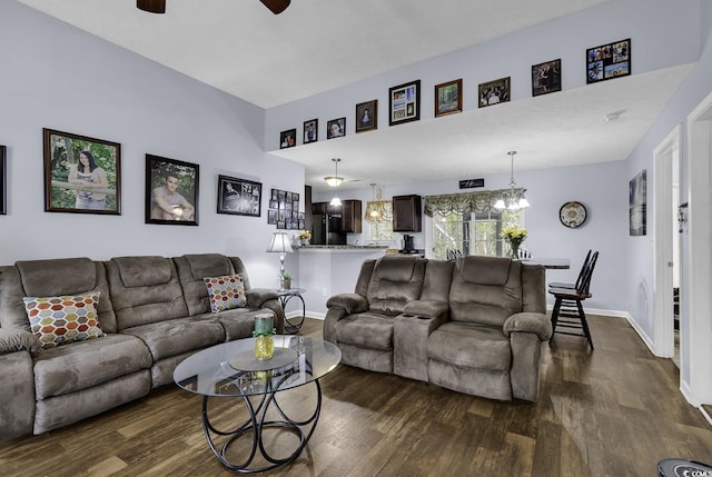 living room with baseboards, dark wood-type flooring, and ceiling fan with notable chandelier