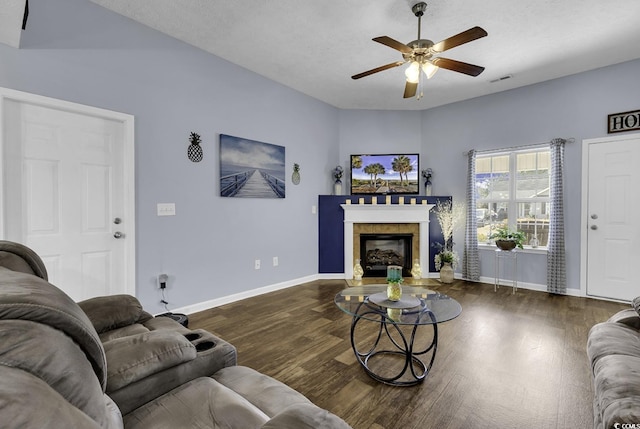 living room featuring a glass covered fireplace, wood finished floors, baseboards, and ceiling fan