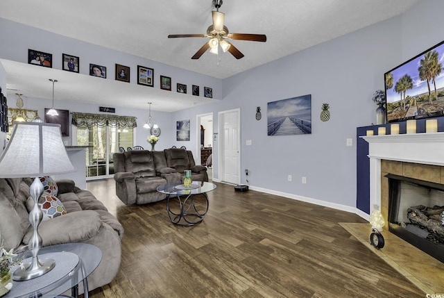 living area with a fireplace, wood finished floors, baseboards, and ceiling fan with notable chandelier