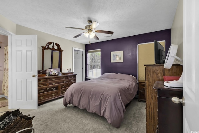 carpeted bedroom featuring a textured ceiling, visible vents, and a ceiling fan