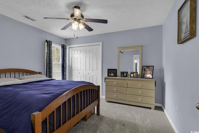 carpeted bedroom with baseboards, a textured ceiling, visible vents, and a closet