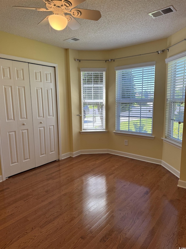 1205 Woodruff Ct, Conway, SC 29526 - unfurnished bedroom featuring dark wood-style flooring, a textured ceiling, multiple windows, and ceiling fan