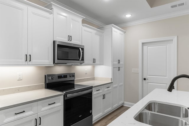 3329 Hughes Gasque Rd, Aynor, SC 29511 - kitchen with stainless steel appliances, crown molding, light wood-style flooring, white cabinets, and light stone counters