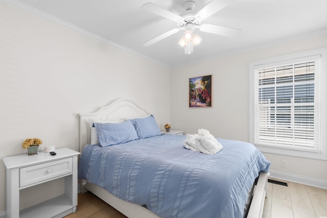 bedroom with visible vents, crown molding, baseboards, a ceiling fan, and light wood finished floors