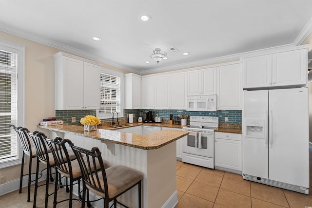 kitchen featuring plenty of natural light, a sink, a peninsula, and white appliances