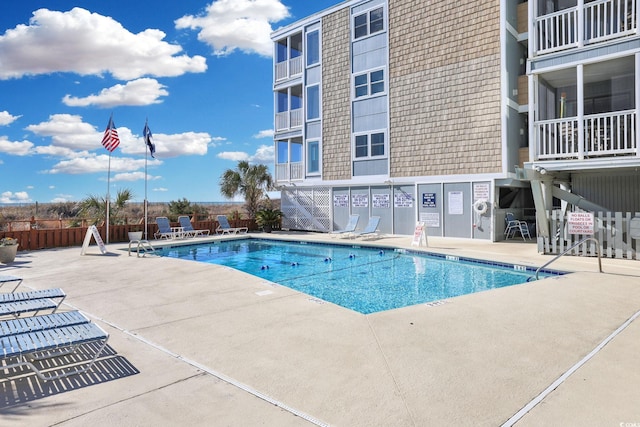 pool with a patio area and fence