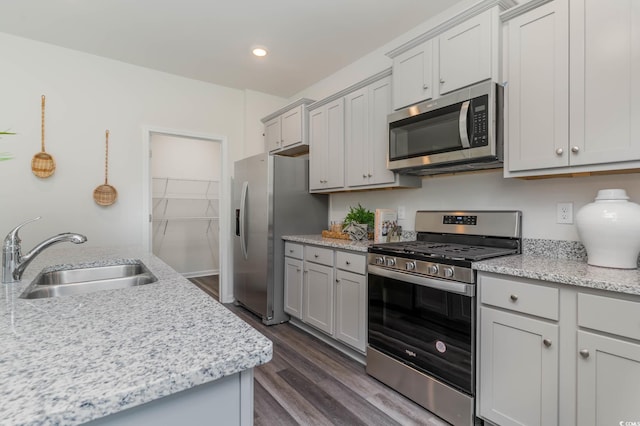 kitchen featuring stainless steel appliances, a sink, dark wood-type flooring, gray cabinets, and recessed lighting