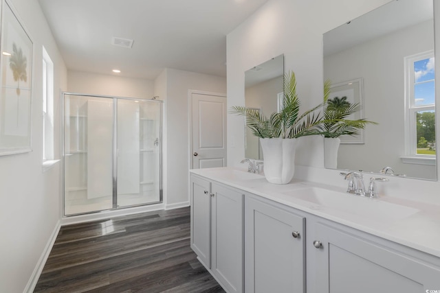 full bath with a shower stall, wood finished floors, double vanity, baseboards, and recessed lighting