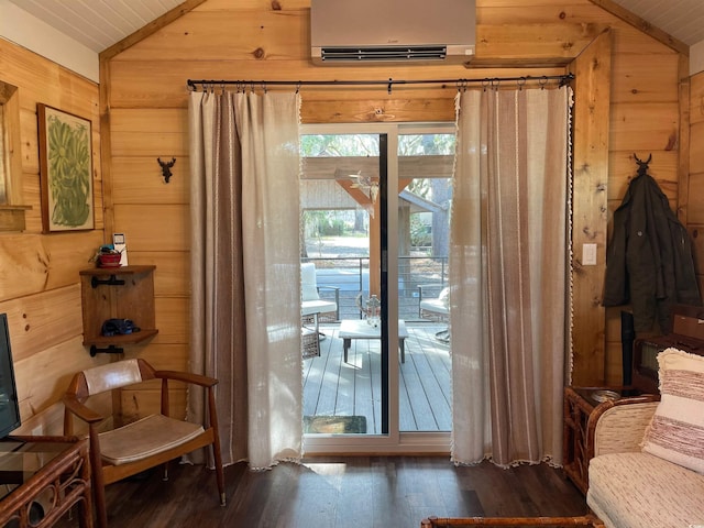 doorway to outside featuring wooden walls, an AC wall unit, wood finished floors, and vaulted ceiling