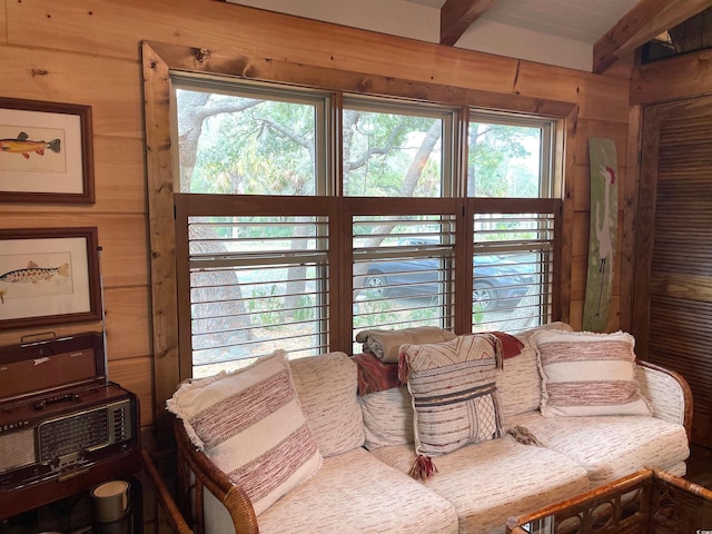living area with beamed ceiling and wood walls