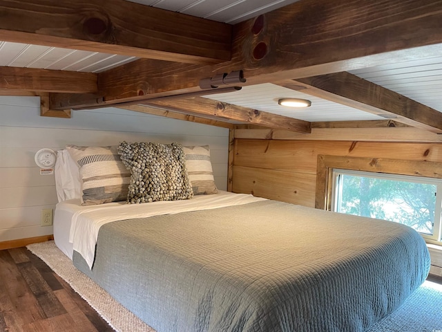 bedroom with beamed ceiling, wooden walls, and wood finished floors