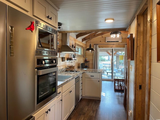 kitchen with dark wood-style floors, stainless steel appliances, light countertops, white cabinetry, and wall chimney range hood