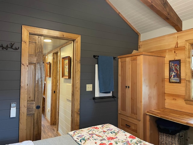 bedroom featuring vaulted ceiling with beams and wood walls
