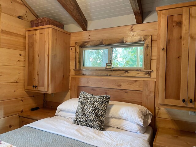 bedroom featuring beamed ceiling, wood walls, and wooden ceiling