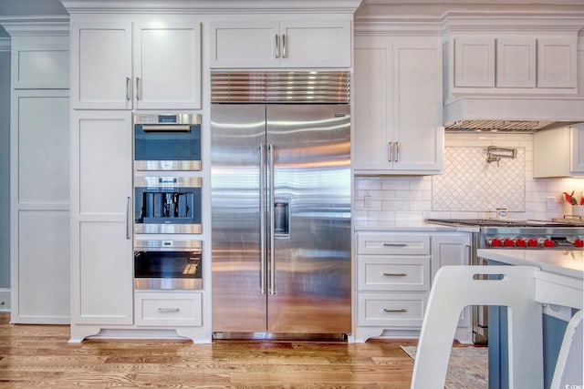 2425 S Bay St, Georgetown, SC 29440 - kitchen featuring stainless steel appliances, premium range hood, white cabinetry, light countertops, and tasteful backsplash