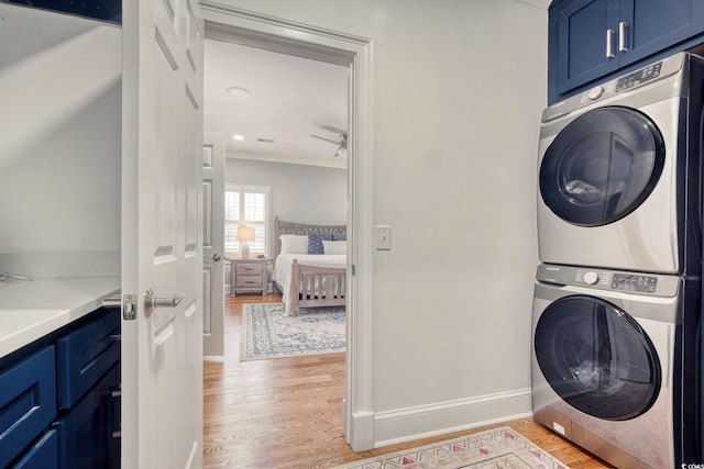 2425 S Bay St, Georgetown, SC 29440 - laundry area featuring cabinet space, stacked washer / drying machine, light wood-style flooring, ornamental molding, and baseboards