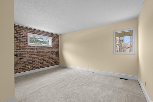 5616 N Kings Hwy, Myrtle Beach, SC 29577 - carpeted empty room featuring plenty of natural light, brick wall, baseboards, and a textured ceiling