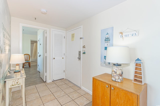 corridor featuring light tile patterned flooring and baseboards