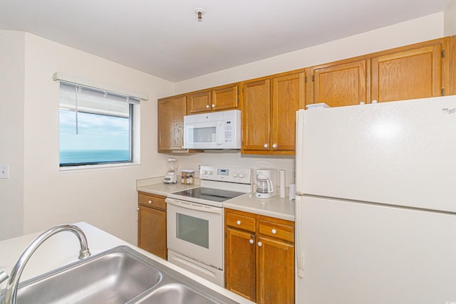 kitchen with white appliances, brown cabinetry, a sink, and light countertops