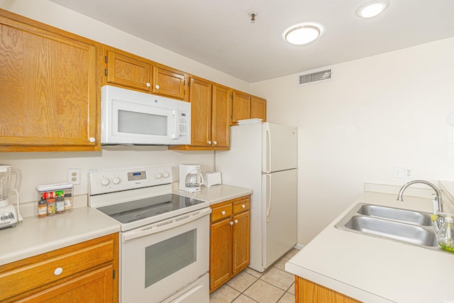 kitchen featuring white appliances, a sink, light tile patterned floors, light countertops, and brown cabinets