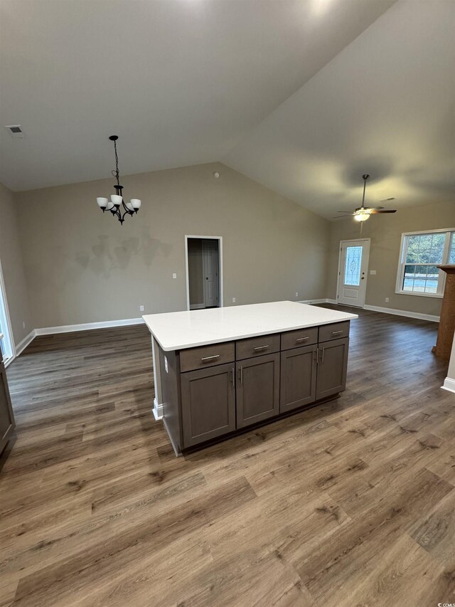 kitchen with open floor plan, wood finished floors, light countertops, and vaulted ceiling