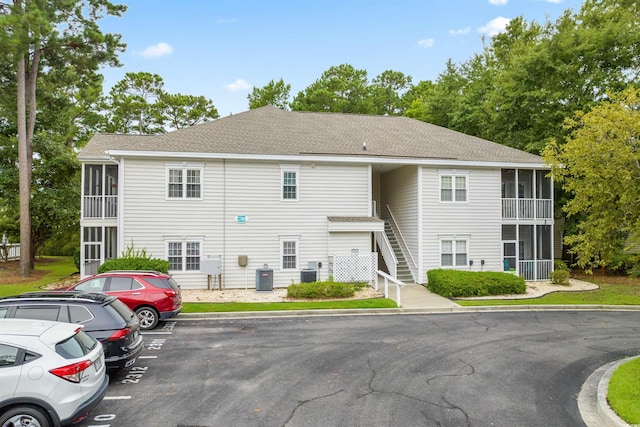 view of property featuring stairs, central AC unit, and uncovered parking