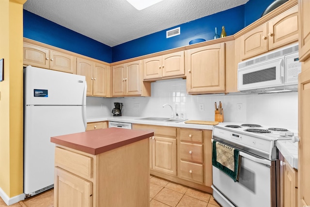 kitchen featuring visible vents, a sink, light tile patterned floors, light brown cabinets, and white appliances