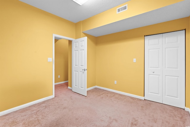 unfurnished bedroom with carpet floors, baseboards, a closet, and visible vents