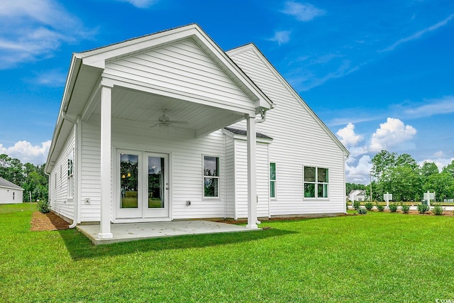 rear view of house featuring ceiling fan, a patio area, and a lawn