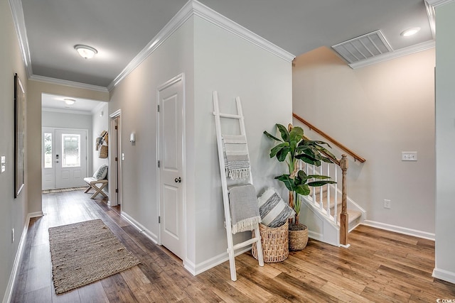 hallway featuring wood finished floors, ornamental molding, and stairs