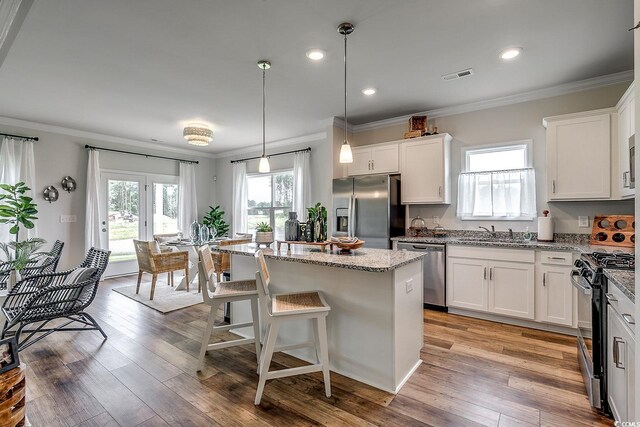 kitchen with visible vents, a sink, ornamental molding, stainless steel appliances, and a kitchen island