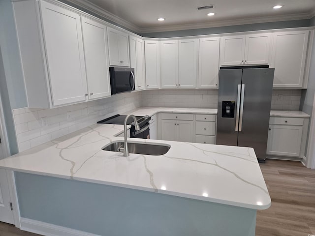 605 15th Ave S, North Myrtle Beach, SC 29582 - kitchen with stainless steel refrigerator with ice dispenser, a peninsula, white cabinets, tasteful backsplash, and ornamental molding