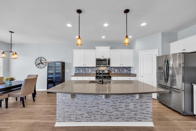 3304 Candytuft Dr, Conway, SC 29526 - kitchen with appliances with stainless steel finishes, backsplash, light wood-type flooring, white cabinets, and a center island with sink