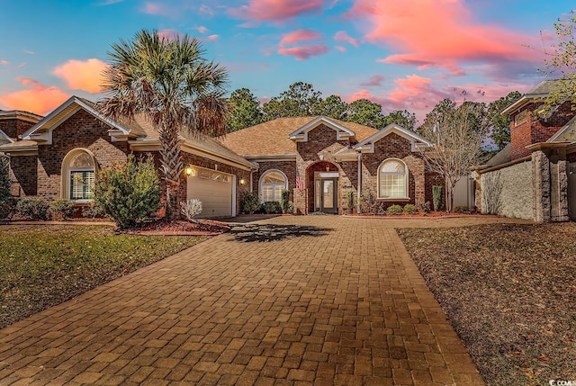view of front facade featuring decorative driveway, brick siding, and a garage