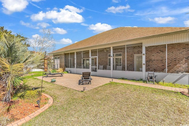 rear view of property featuring a sunroom, a patio, a lawn, and brick siding