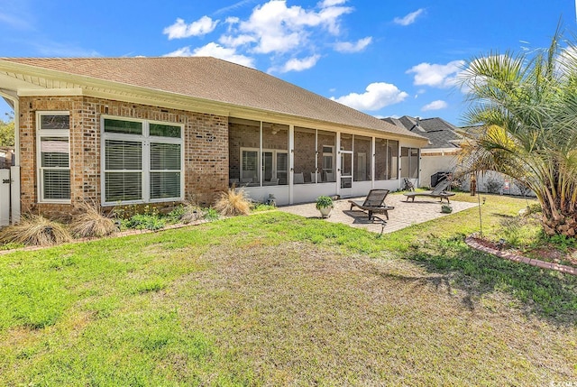 rear view of property with fence, a patio, a lawn, brick siding, and a sunroom