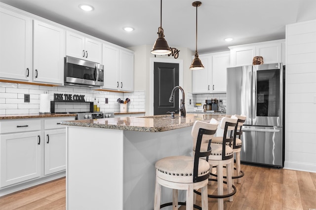 134 Winding Path Dr, Loris, SC 29569 - kitchen featuring stainless steel appliances, light wood-style flooring, dark stone countertops, white cabinets, and a sink
