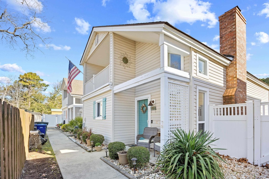 1902-B Hillside Dr S, North Myrtle Beach, SC 29582 - view of front of property featuring a balcony, a fenced backyard, and a chimney