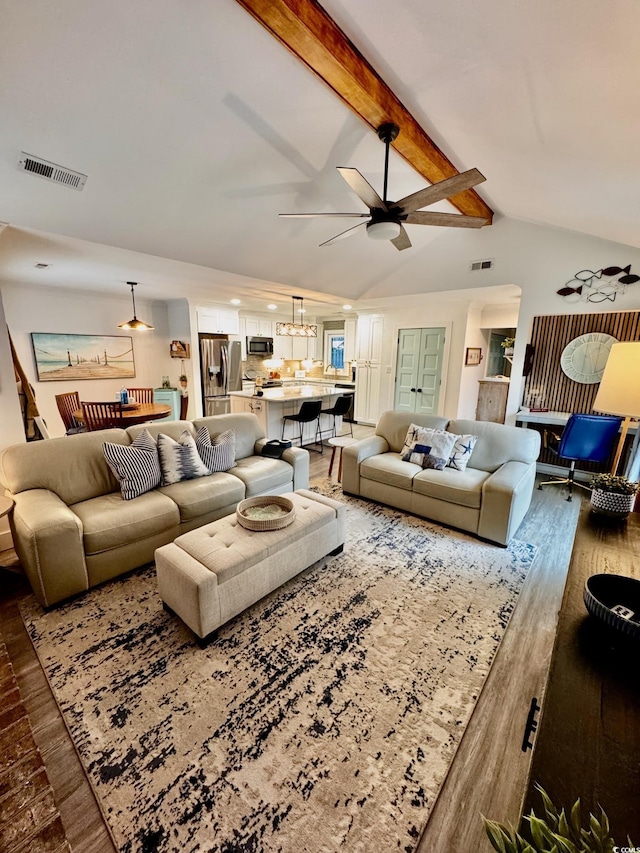 living room with lofted ceiling with beams, visible vents, ceiling fan with notable chandelier, and wood finished floors