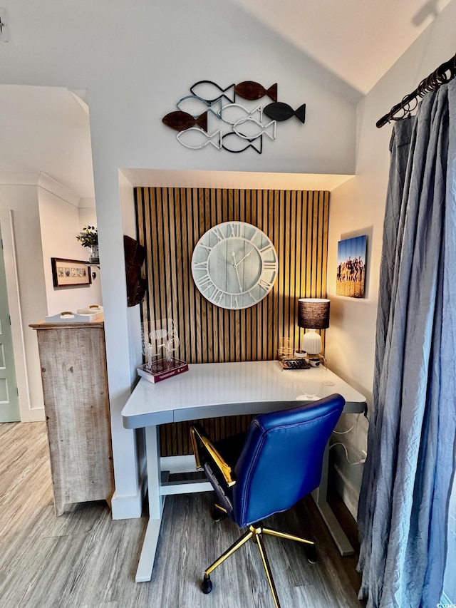 dining space featuring lofted ceiling, built in desk, and wood finished floors