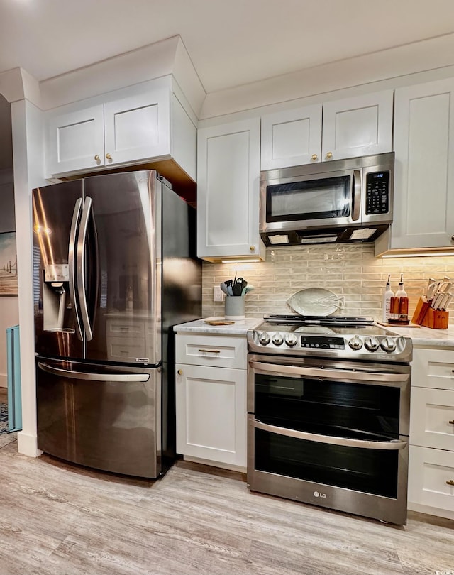 kitchen with white cabinets, stainless steel appliances, light wood-type flooring, and tasteful backsplash