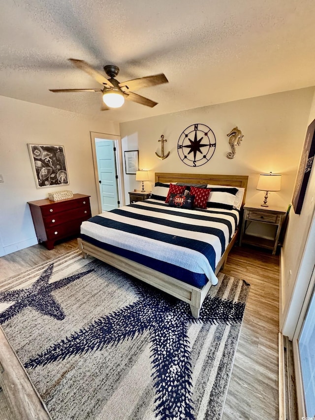 bedroom with a ceiling fan, a textured ceiling, and wood finished floors
