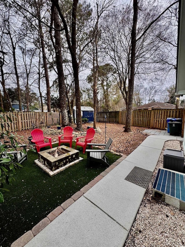 view of yard with a fenced backyard, a fire pit, an outbuilding, and a storage shed