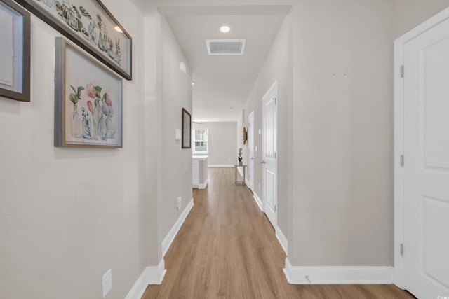 hall with light wood-style flooring and baseboards