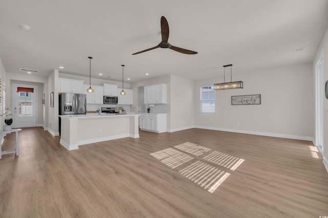 unfurnished living room featuring baseboards, plenty of natural light, ceiling fan, light wood-type flooring, and recessed lighting