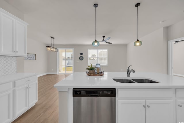 kitchen with stainless steel dishwasher, a sink, light wood-type flooring, tasteful backsplash, and light countertops